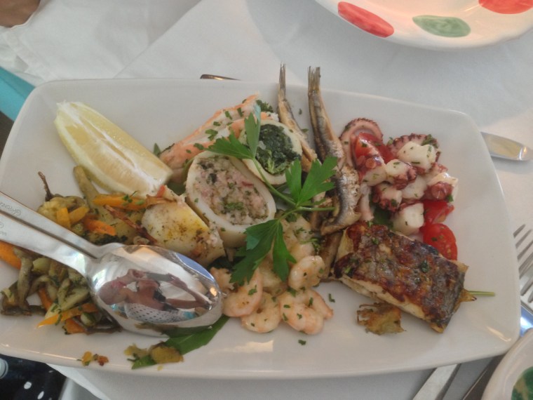 Another reach plate of fresh seafood including marinated anchovies, fresh Gulf shrimp, octopus,  stuffed squids, grilled fish and langostinos